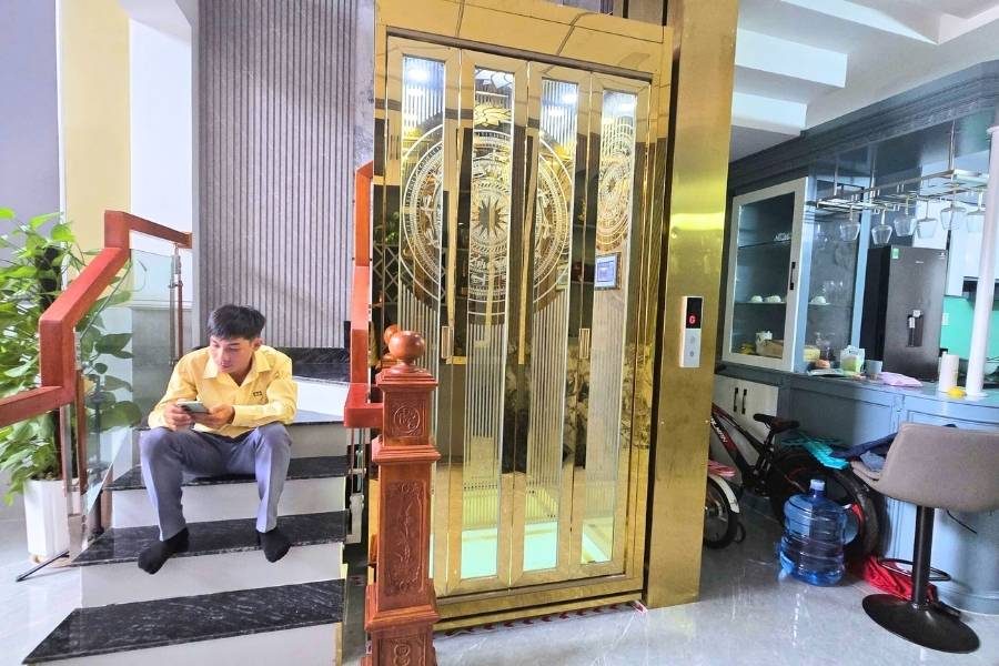 Cabin kính viền vàng gọn cạnh cầu thang trong phòng khách