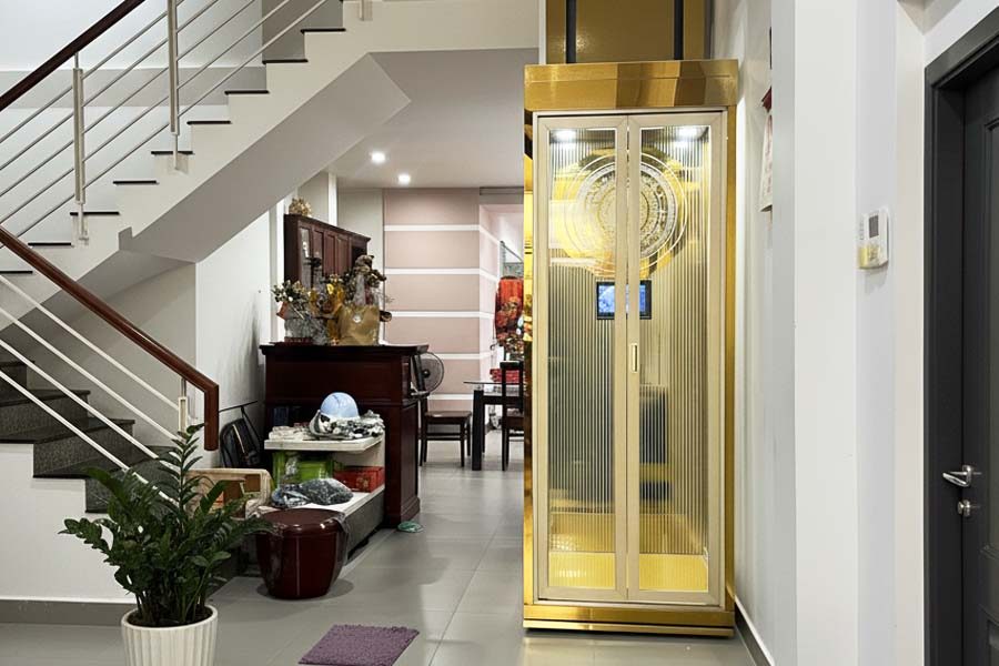 Thang máy mini kính viền vàng trong phòng khách nhà phố